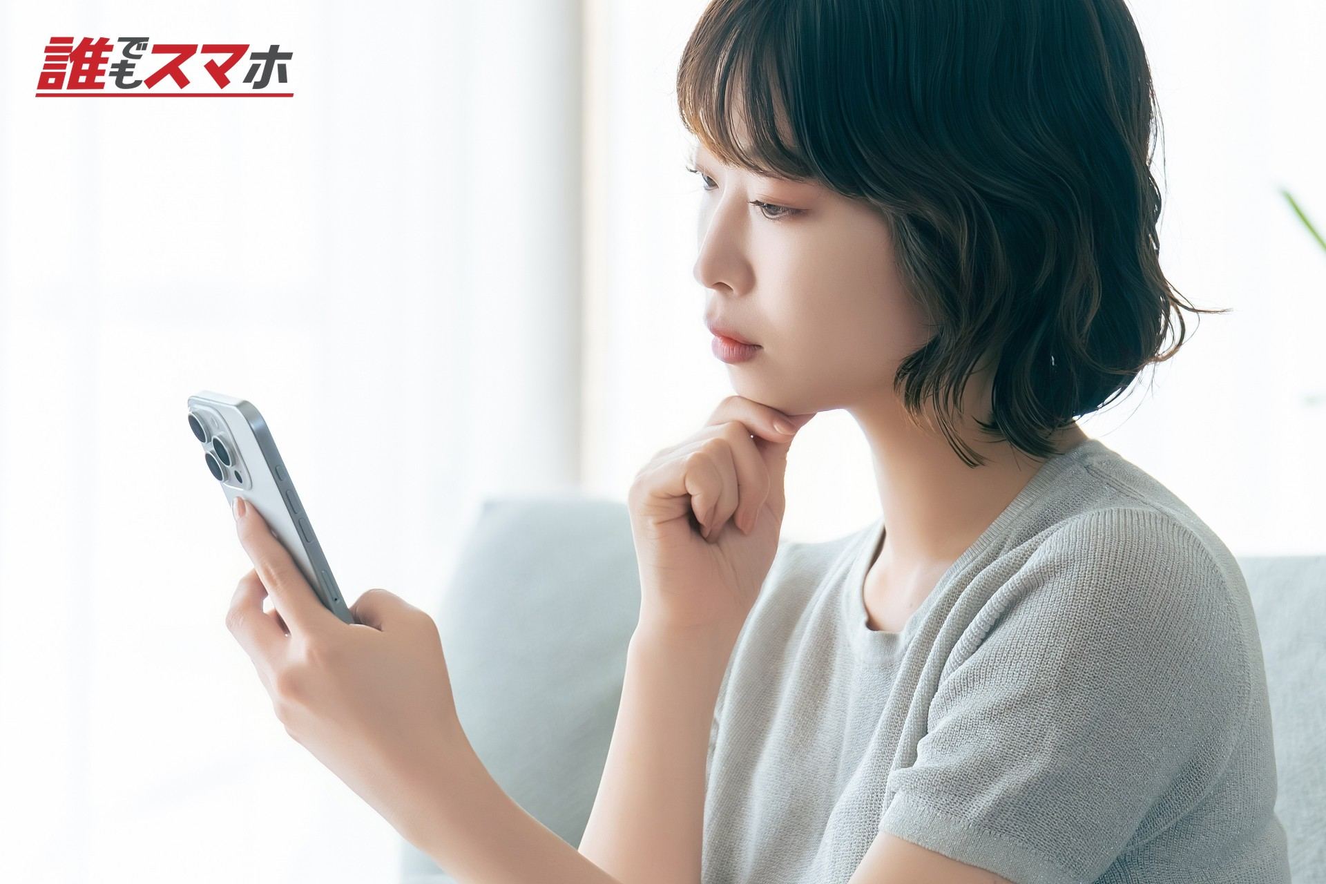 スマホを見ながら考えごとをする女性