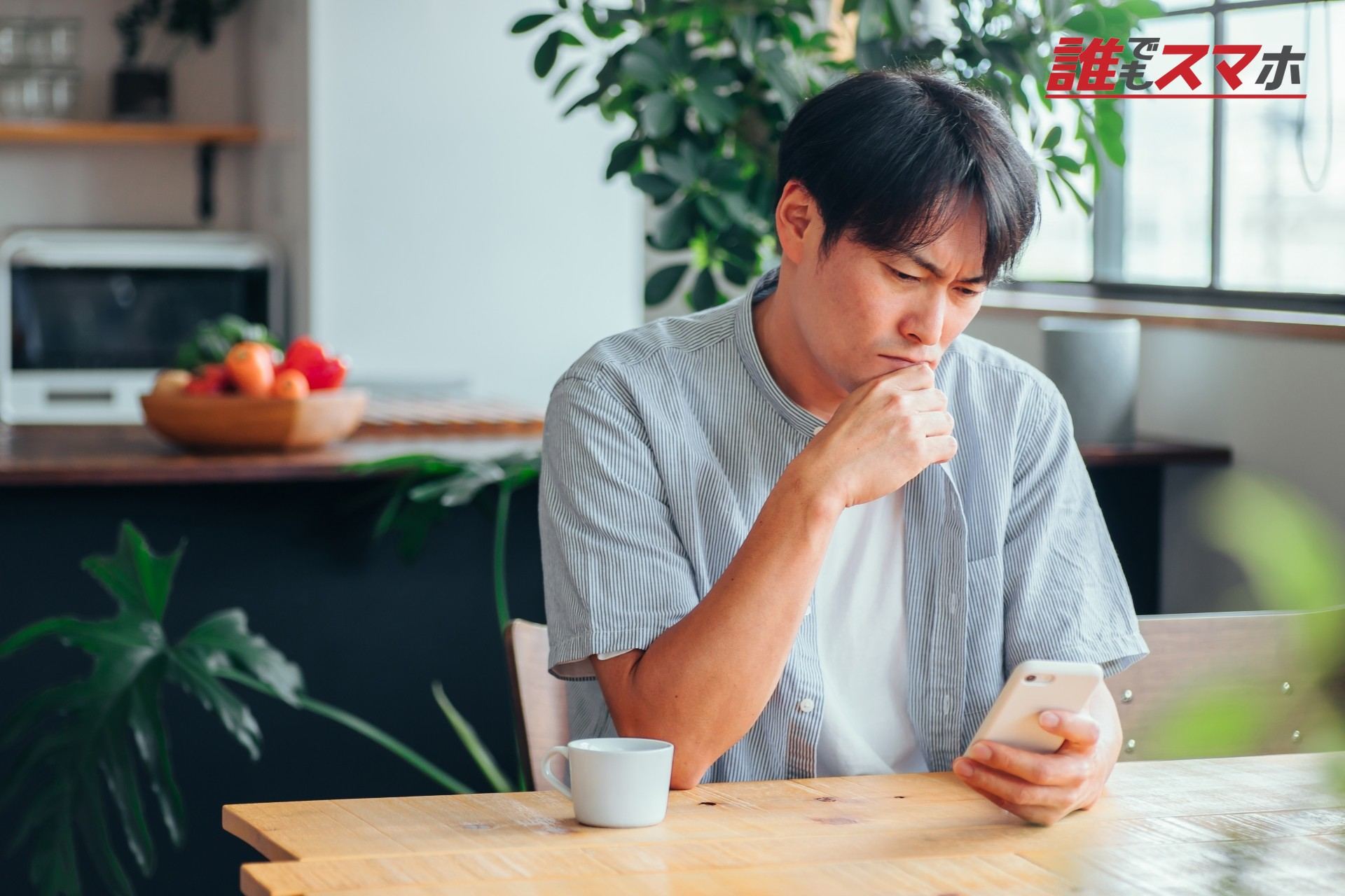 スマホを見て悩む男性