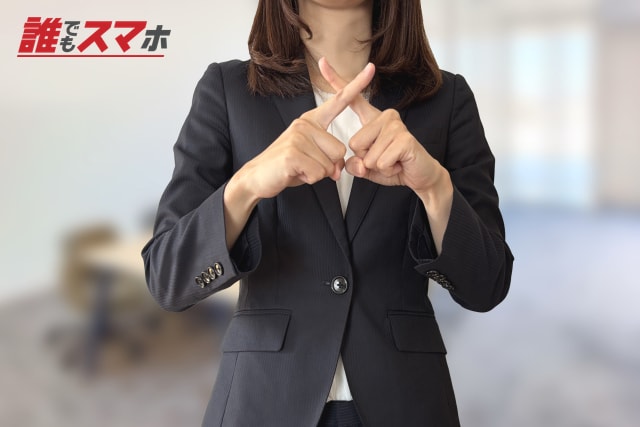 指でバツ印を作る女性