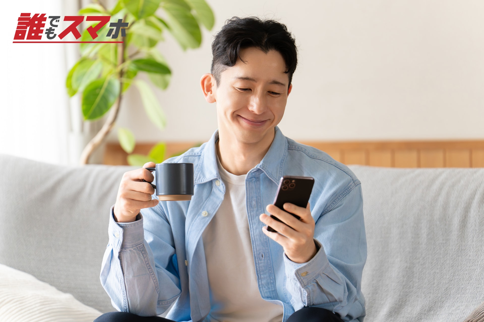 飲み物とスマートフォンを持つ男性