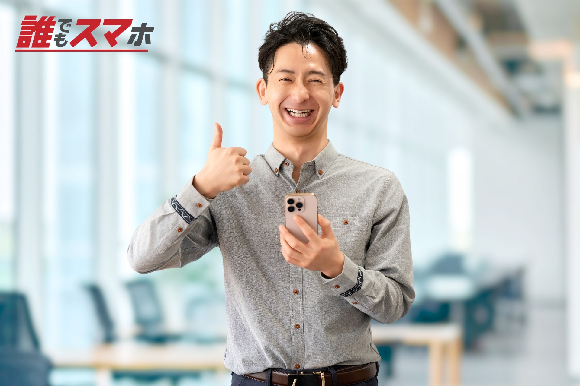 スマートフォンを持って親指を立てる男性