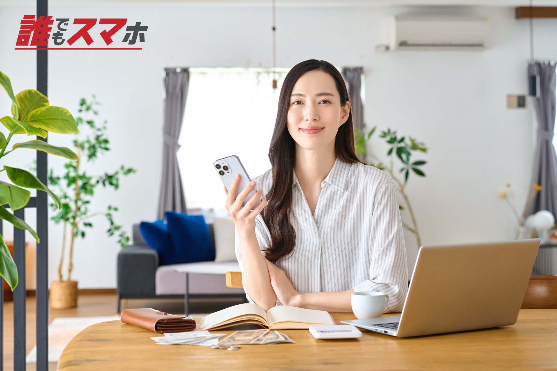 パソコンの前でスマートフォンを持つ女性