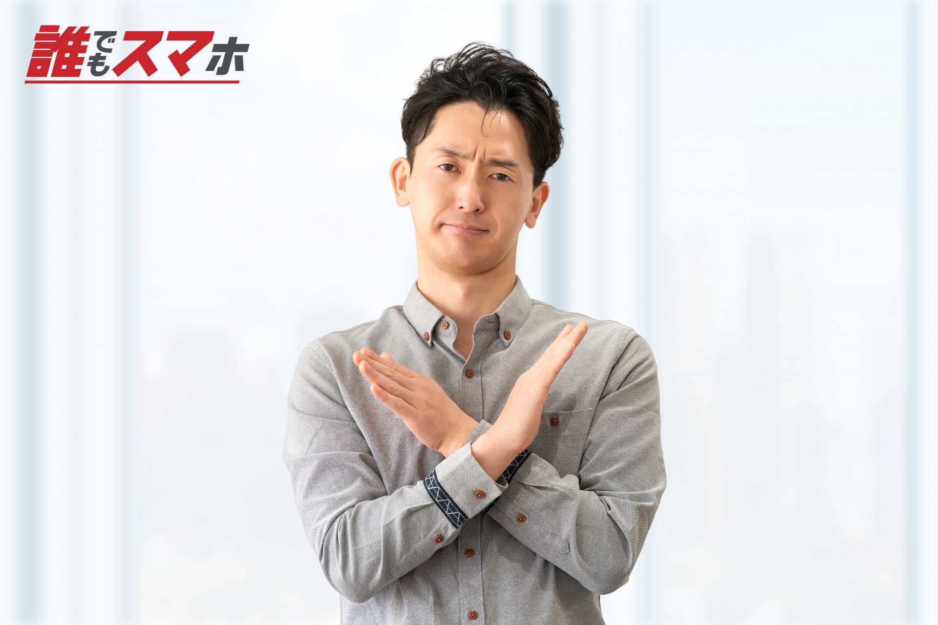 腕でバツ印を作る男性