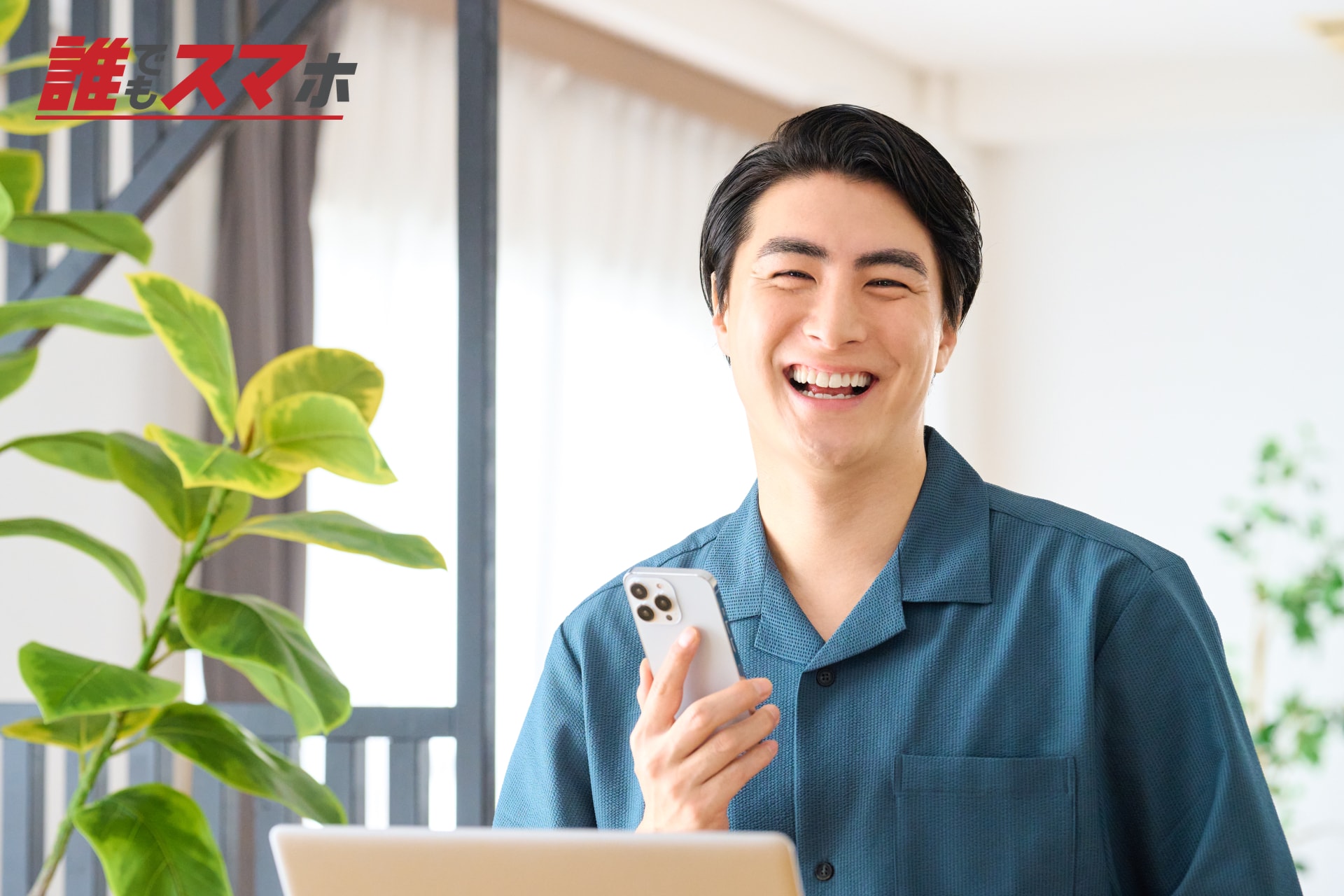 スマートフォンを持って笑う男性