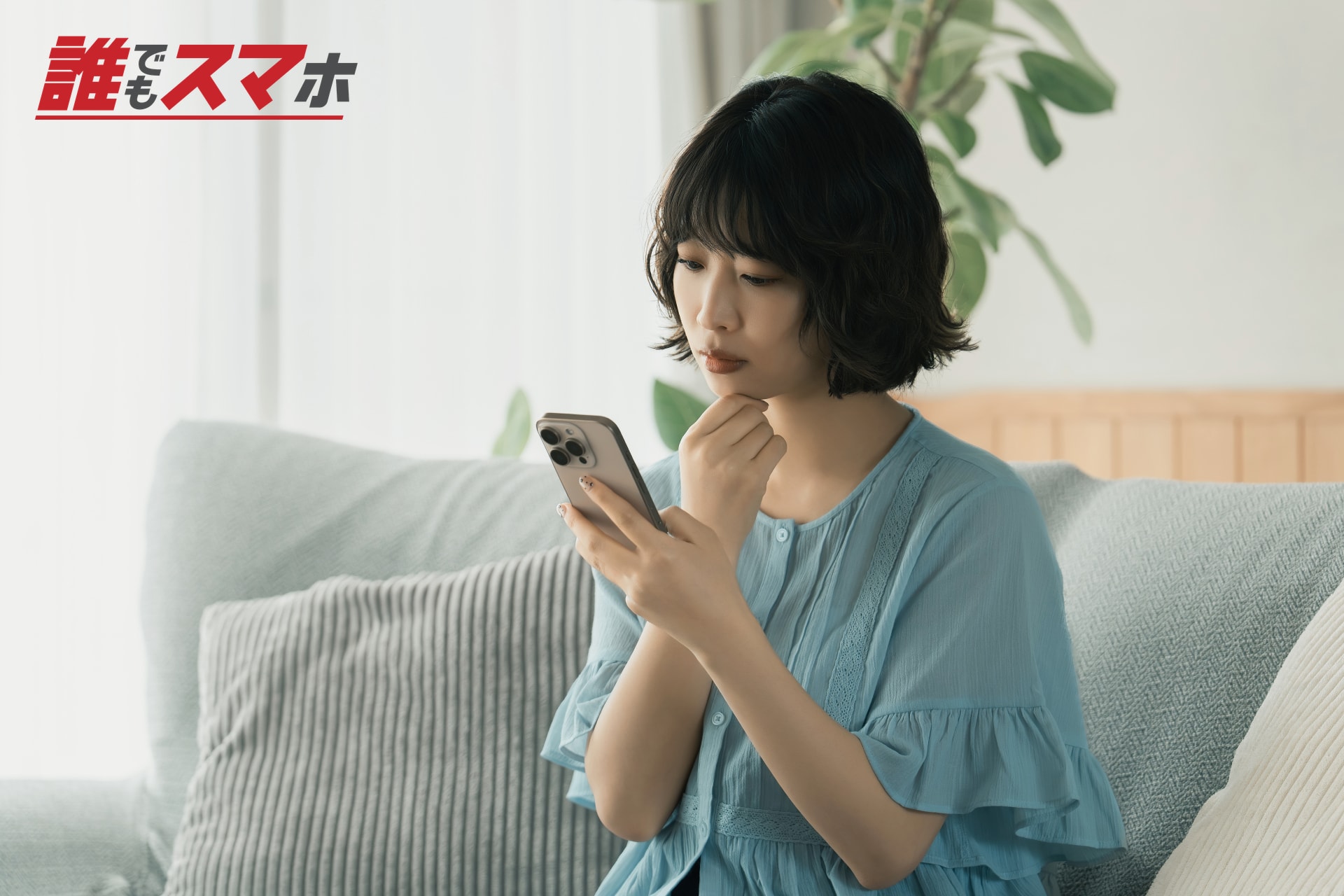 ソファでスマートフォンを見て考える女性