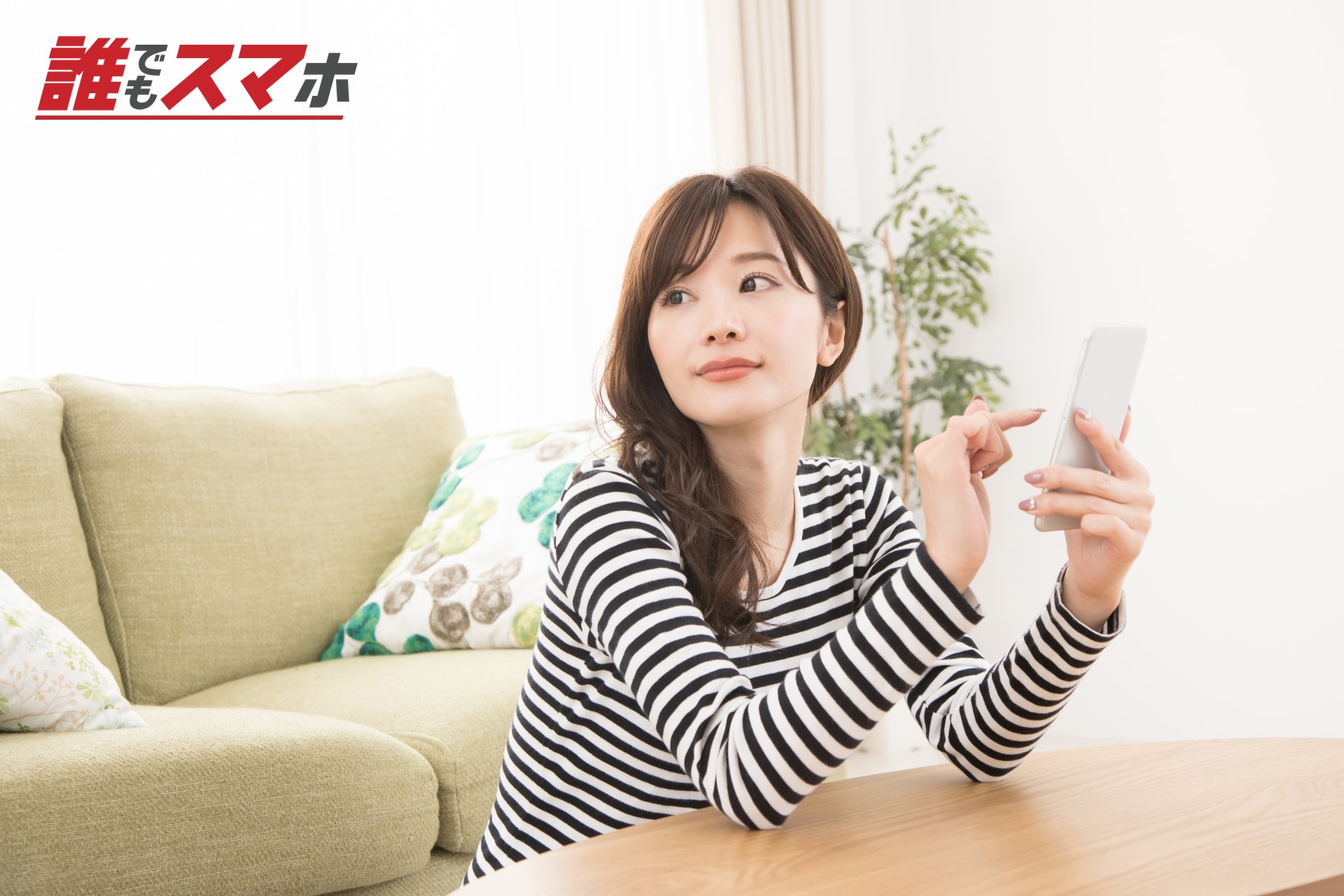 スマートフォンを持って指を立てる女性
