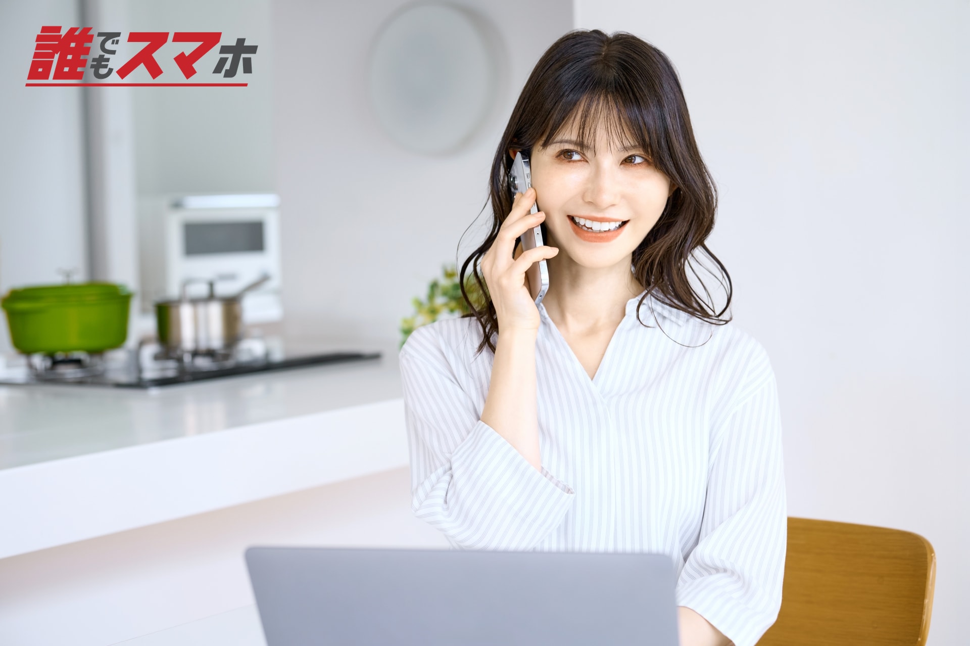 パソコンの前で電話する女性