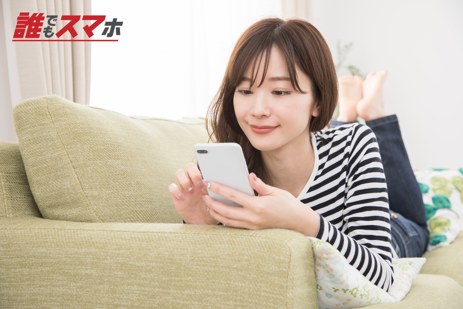 ソファでくつろぎながらスマートフォンを使う女性