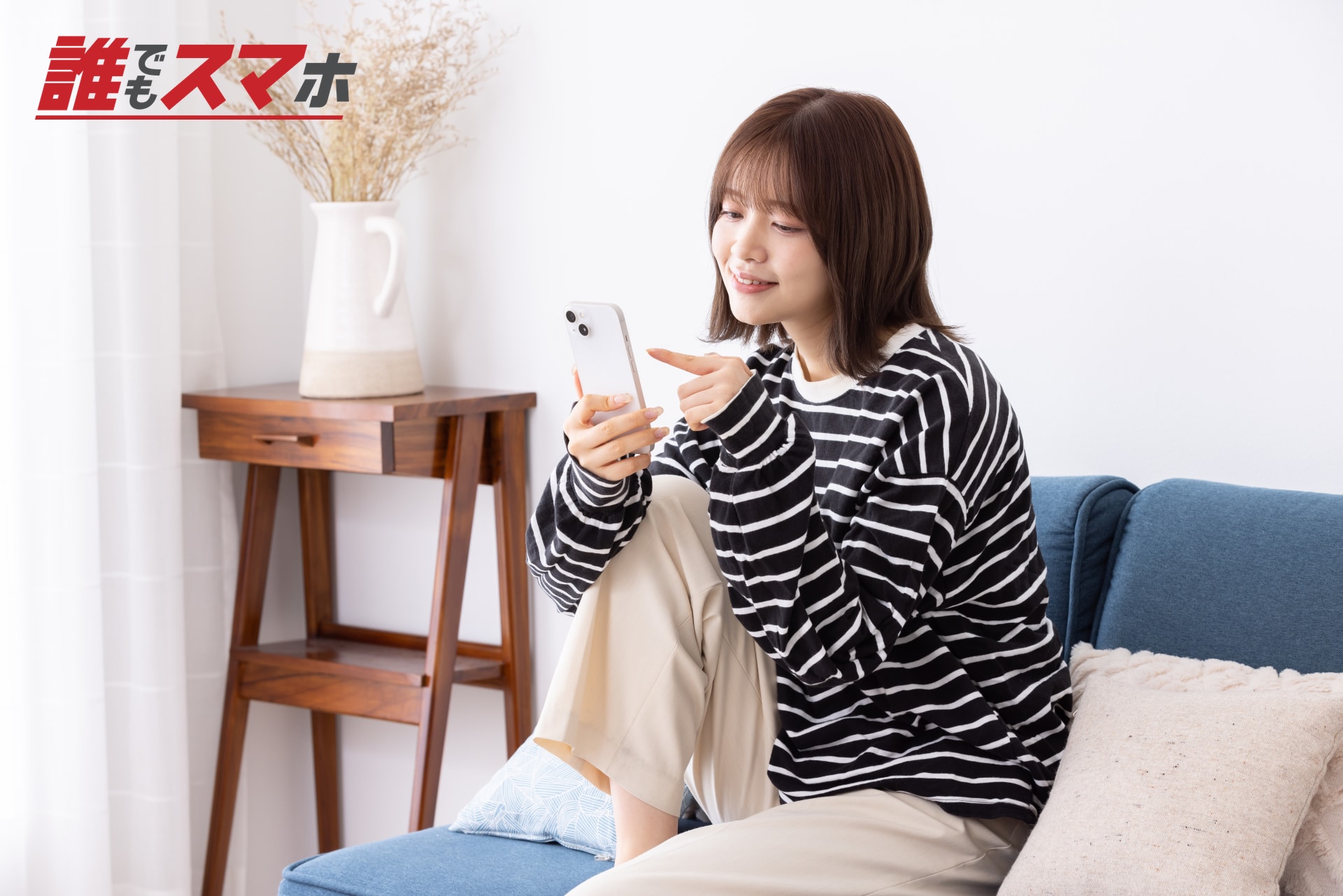ソファでスマートフォンを見る女性
