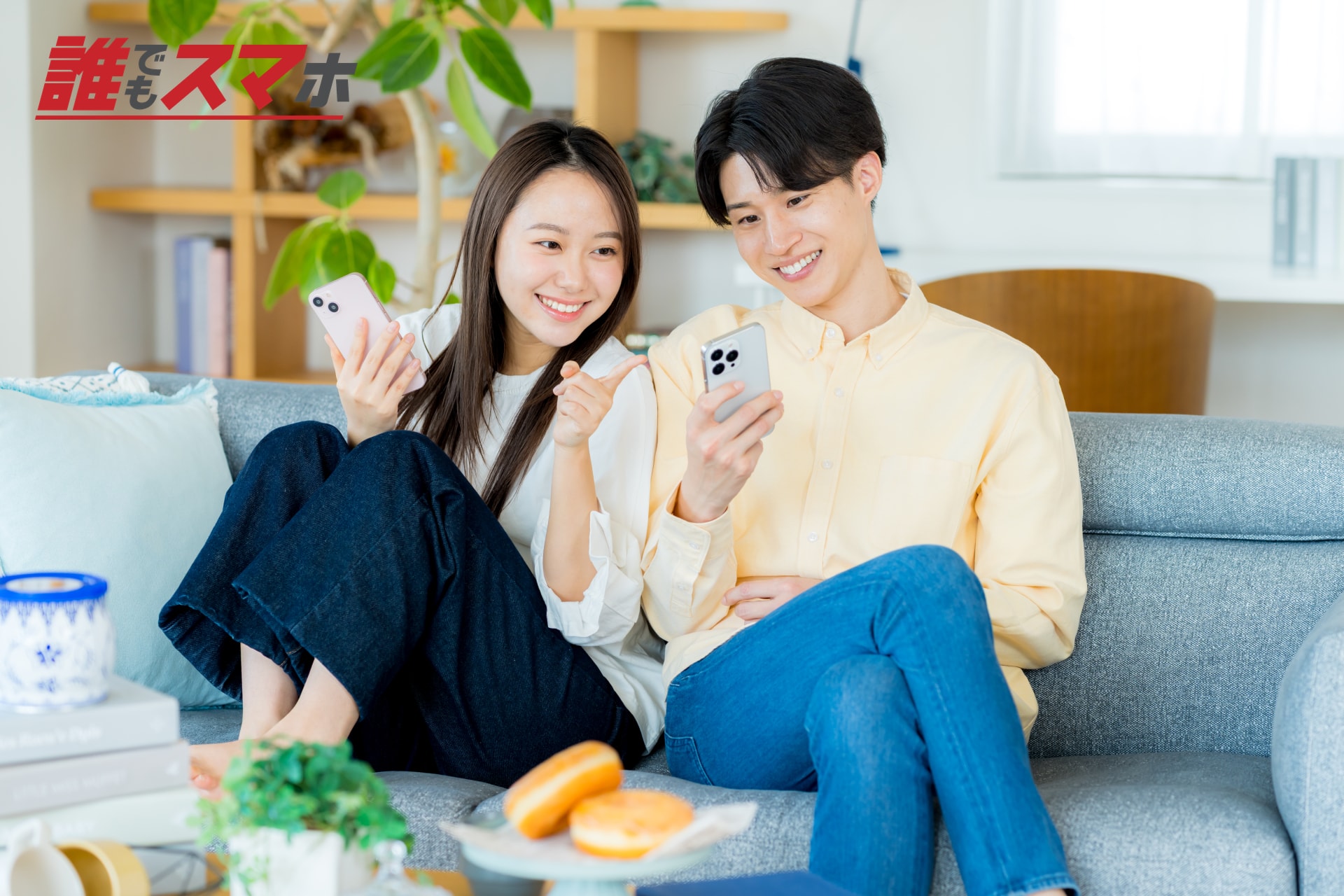 ソファでスマートフォンを見る男女